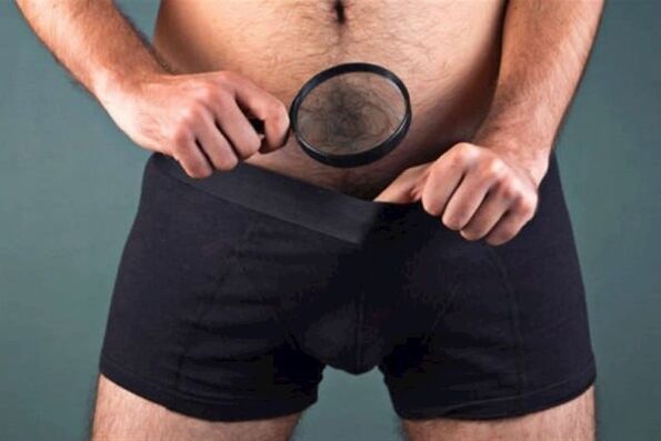 moški s povečevalnim steklom pregleduje svoj penis in ga želi odebeliti